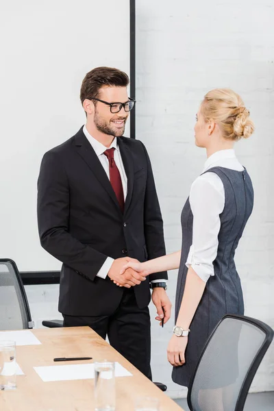 Уверенные деловые партнеры, пожимающие руки в современном офисе — стоковое фото