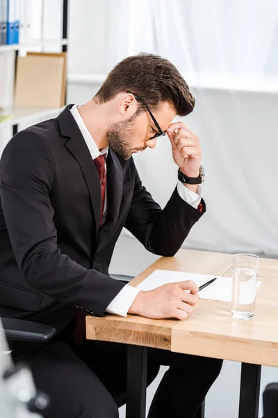 Jeune homme d'affaires concentré travaillant seul au bureau moderne — Photo de stock