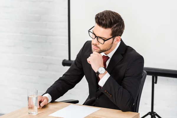 Thoughtful young businessman working alone at modern office — Stock Photo