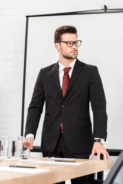 Jeune homme d'affaires confiant debout dans la salle de conférence et regardant loin — Photo de stock