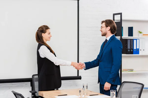 Jóvenes colegas de negocios exitosos estrechando la mano durante la reunión - foto de stock