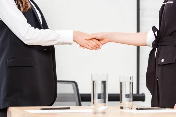 Tiro cortado de empresárias apertando as mãos no escritório moderno — Fotografia de Stock