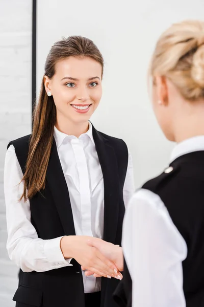 Hermosas mujeres de negocios jóvenes estrechando la mano en la oficina moderna - foto de stock