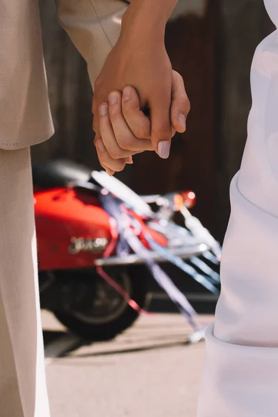 Vista parziale di coppia che si tiene per mano contro scooter rosso — Foto stock