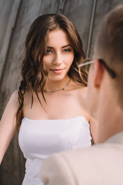 Hermosa novia romántica en vestido de novia blanco mirando al novio - foto de stock