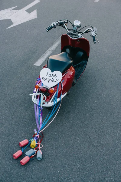Vista posteriore del ciclomotore vintage con lattine colorate, nastri e simbolo del cuore 