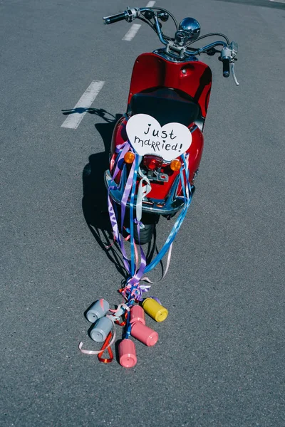 Red scooter with colorful cans, ribbons and 