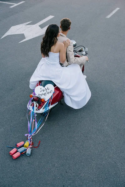 Back view of wedding couple riding scooter with 