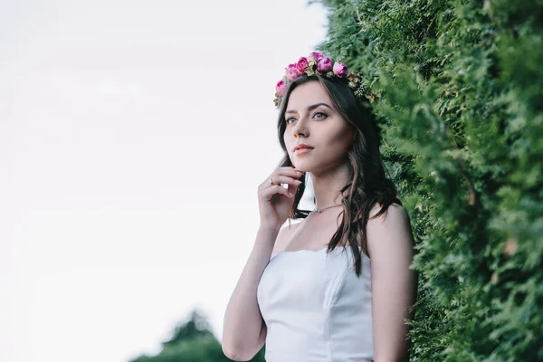 Hermosa esposa posando en vestido de novia blanco tradicional y corona floral - foto de stock