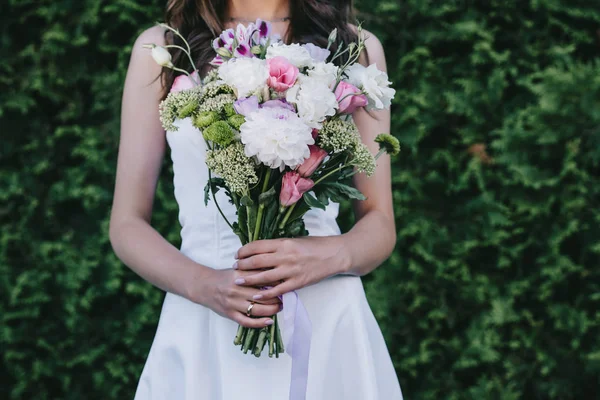 Vista recortada de la novia en vestido blanco tradicional celebración de ramo de boda - foto de stock