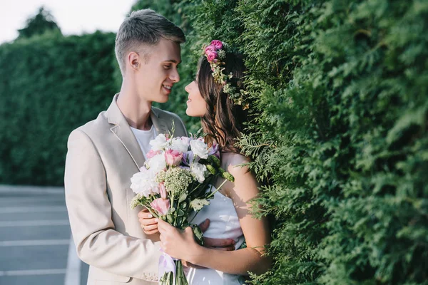 Beautiful wedding couple hugging and holding traditional floral bouquet — Stock Photo