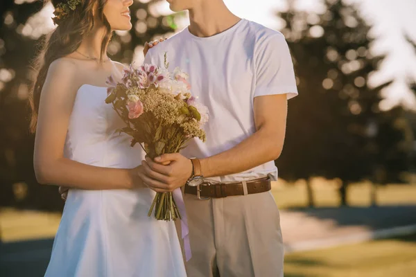 Cropped view of wedding couple holding flower bouquet — Stock Photo