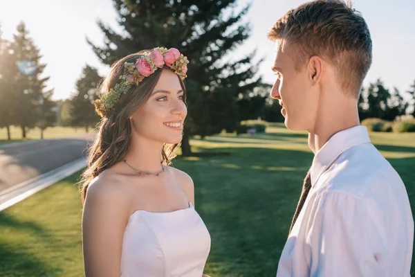 Beautiful happy young wedding couple looking at each other in park — Stock Photo