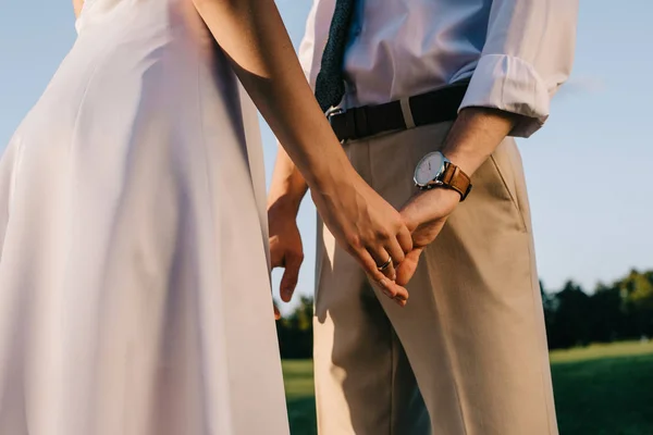 Recortado disparo de romántico joven pareja de boda de la mano en el parque — Stock Photo