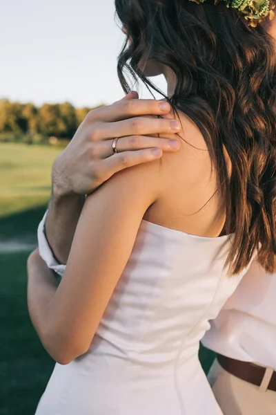 Recortado disparo de romántico joven novio abrazando hermosa novia en el parque - foto de stock