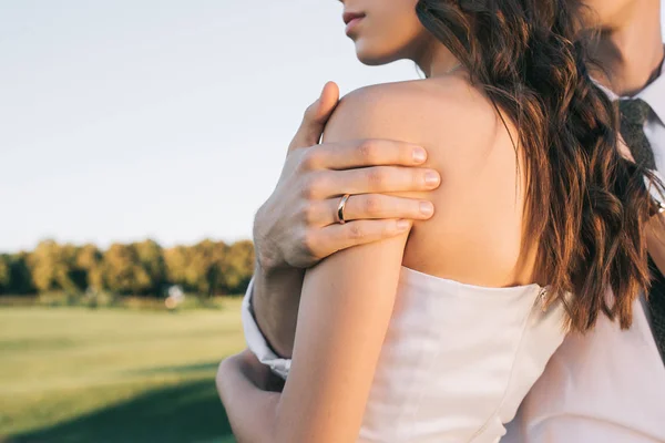 Обрізаний знімок романтичної молодої весільної пари, що обіймається в парку — стокове фото