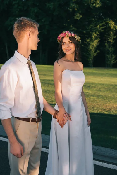 Hermosa romántica joven pareja de boda sonriendo entre sí y caminando juntos en el parque - foto de stock