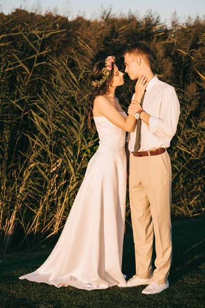 Beau heureux jeune couple tendre mariage en mesure de baiser sur l'herbe verte — Photo de stock