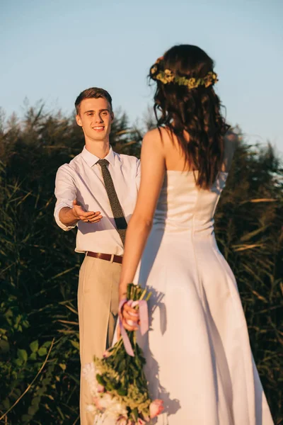 Heureux jeune marié regardant belle mariée tendre avec bouquet de mariage — Photo de stock