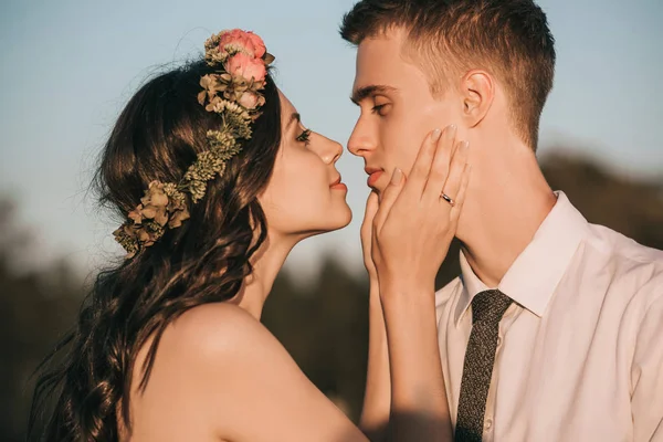 Vista lateral de hermosa pareja feliz boda joven capaz de besar en el parque - foto de stock
