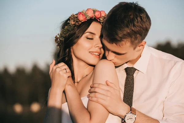 Young groom kissing beautiful smiling bride in park — Stock Photo