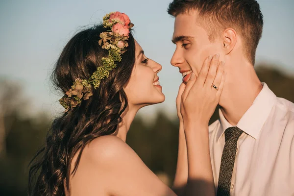 Side view of beautiful happy young wedding couple kissing in park — Stock Photo