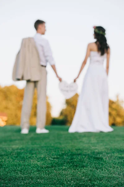 Enfoque selectivo de la joven pareja de boda de pie juntos en el césped verde - foto de stock