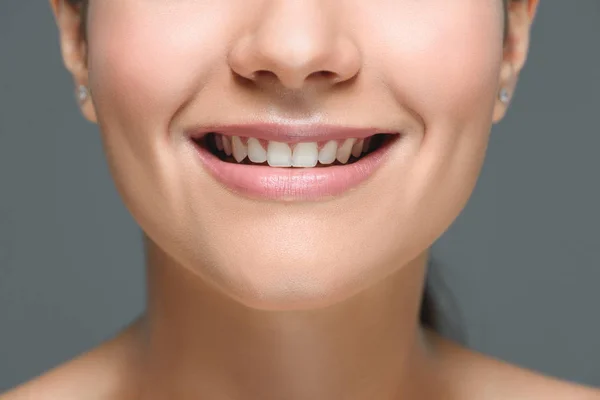 Частичный вид улыбающейся женщины с красивыми белыми зубами, изолированными на сером — стоковое фото