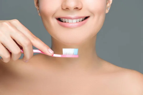 Cropped shot of smiling woman holding tooth brush in hand isolated on white — Stock Photo