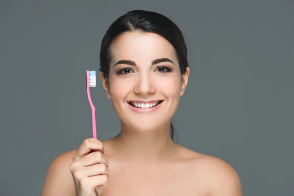 Sonriente morena mujer sosteniendo cepillo de dientes en la mano aislado en blanco - foto de stock