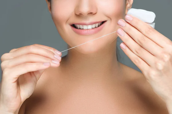 Plan recadré de femme souriante avec de belles dents blanches et fil dentaire isolé sur gris — Photo de stock