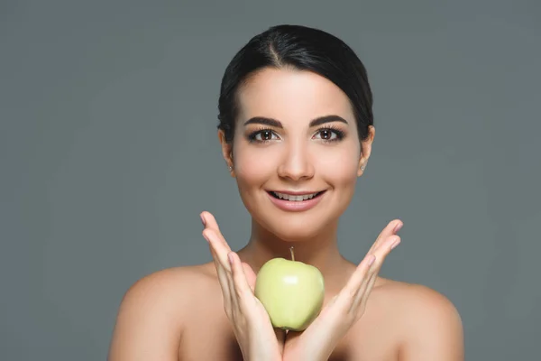 Portrait of young woman with fresh apple in hands isolated on grey — Stock Photo