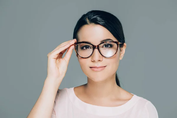 Porträt der schönen brünetten Frau mit Brille, die in die Kamera schaut, isoliert auf grau — Stockfoto