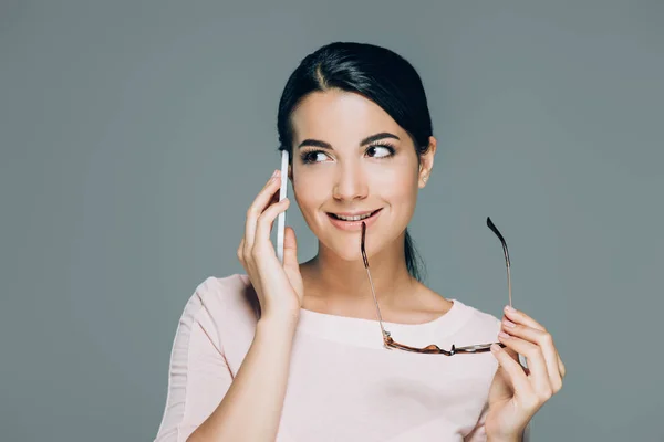 Porträt einer schönen brünetten Frau mit Brille, die auf einem Smartphone spricht, isoliert auf grau — Stockfoto