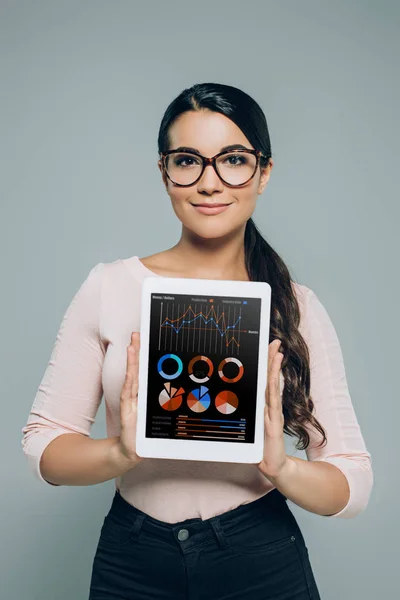 Жінка показує цифровий планшет з приладом для бізнес-карт і графіків, ізольований на сірому — стокове фото