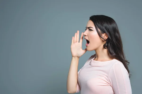 Attractive emotional girl gesturing and yelling, isolated on grey — Stock Photo
