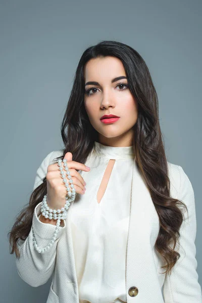 Portrait of attractive girl posing in white suit with necklace, isolated on grey — Stock Photo