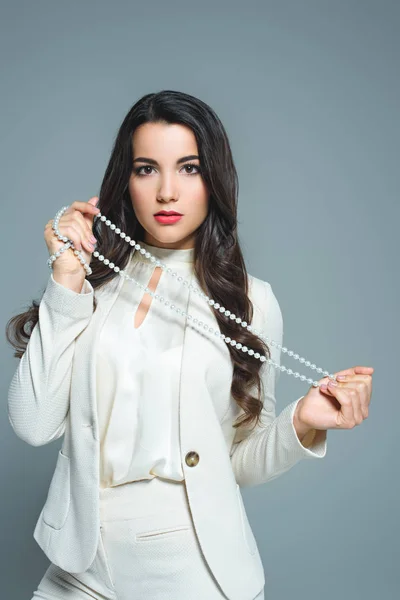 Atractiva mujer posando en traje blanco con collar, aislado en gris - foto de stock