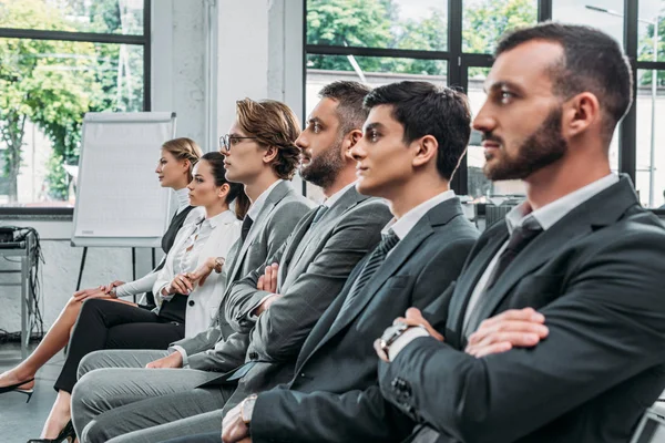 Homens de negócios e mulheres de negócios sentados em cadeiras durante a formação em hub — Fotografia de Stock