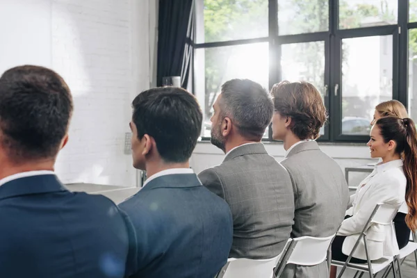 Rear view of businesspeople sitting on chairs during training in hub — Stock Photo