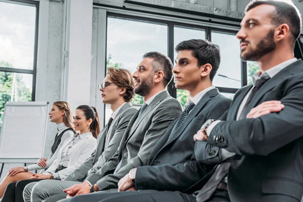 Geschäftsleute sitzen beim Training in Hub auf Stühlen und schauen weg — Stockfoto