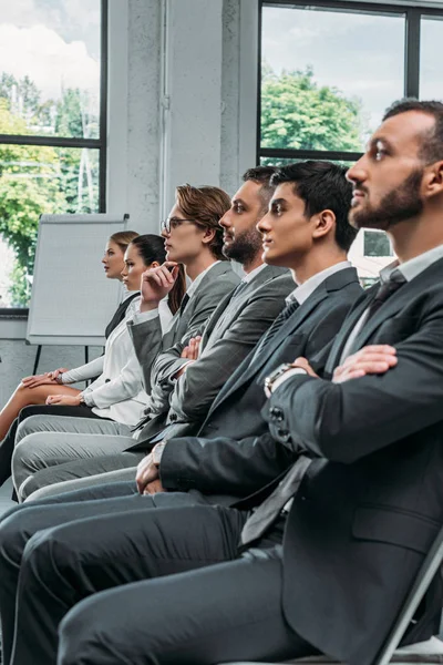 Side view of businesspeople sitting on chairs during training in hub — Stock Photo