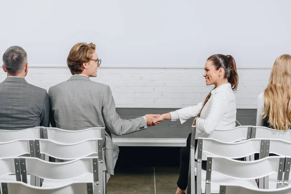 Side view of businessman and businesswoman shaking hands during business training in hub — Stock Photo