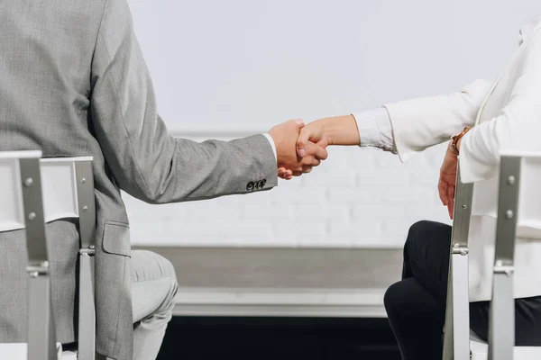 Cropped image of businessman and businesswoman shaking hands during business training in hub — Stock Photo
