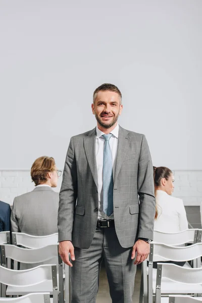 Smiling handsome coach looking at camera during business training in hub — Stock Photo