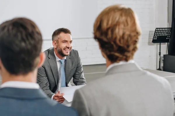 Sonriente entrenador de negocios mirando hacia otro lado en el centro - foto de stock