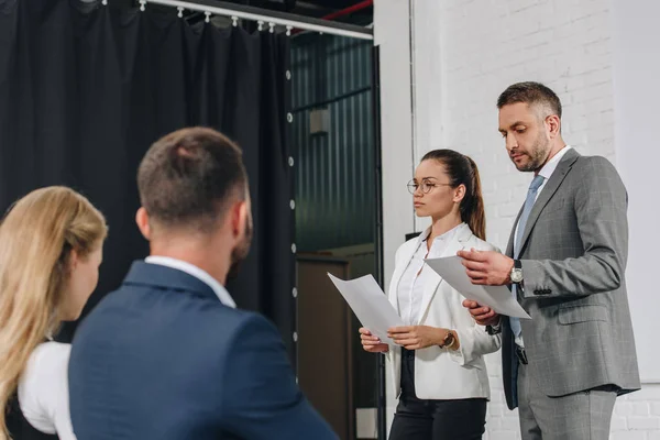 Business trainers standing on stage with documents in hub — Stock Photo