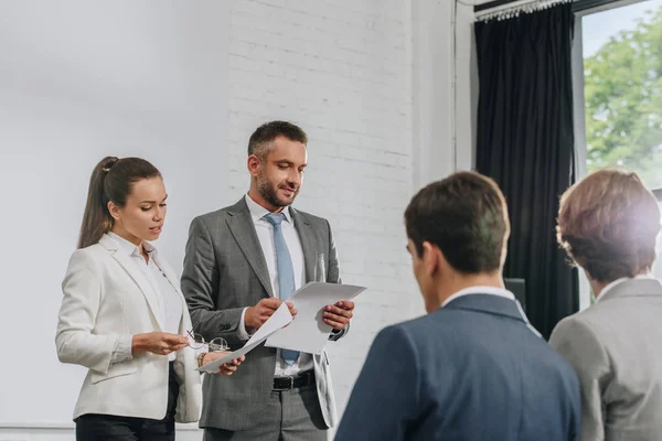 Business-Trainer stehen mit Dokumenten in der Hand auf der Bühne — Stockfoto