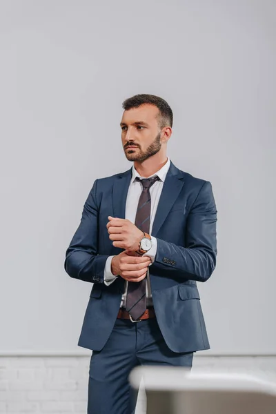 Handsome businessman buttoning sleeve in hub — Stock Photo