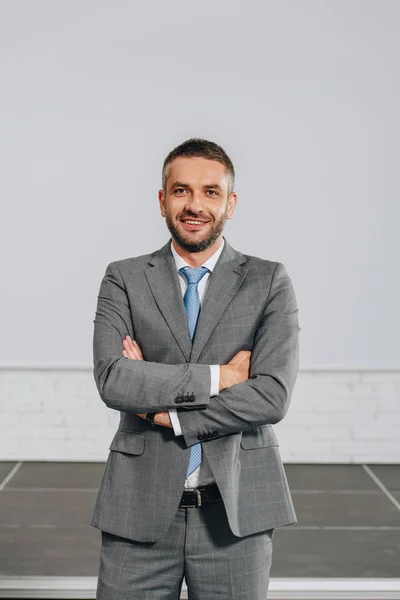 Smiling handsome businessman with crossed arms looking at camera in hub — Stock Photo